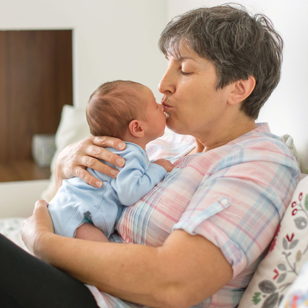 Grandmother kissing newborn baby on the nose