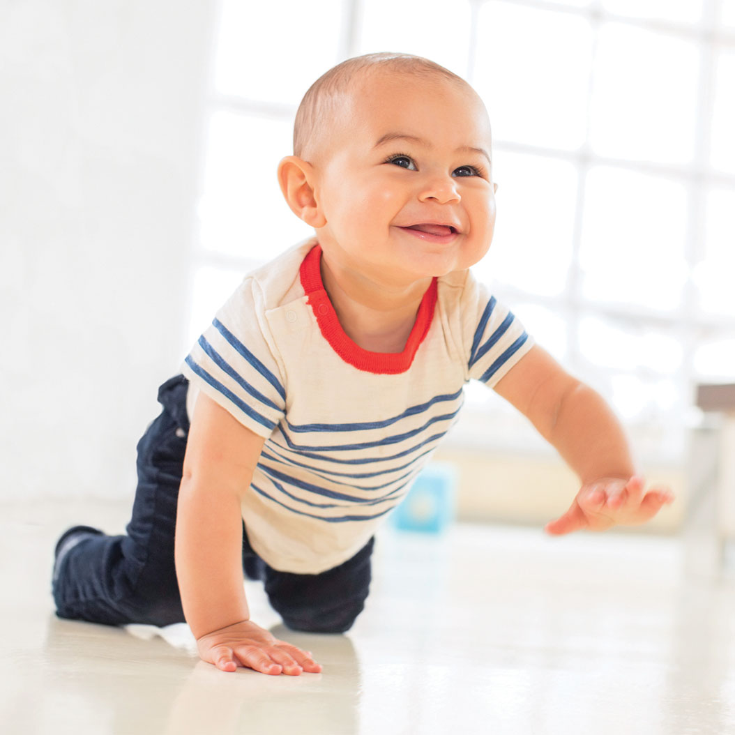 Smiling toddler crawling on a wood floor