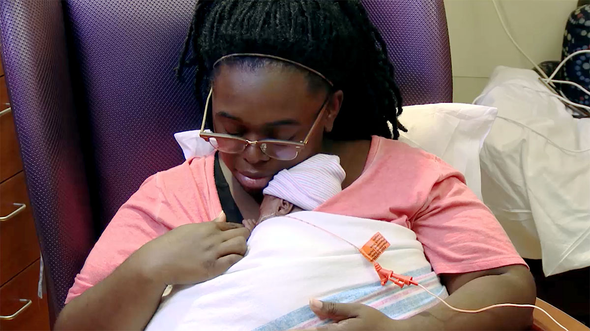 A still from Understanding the NICU & Your Baby Video showing a woman doing kangaroo care with her premature baby.
