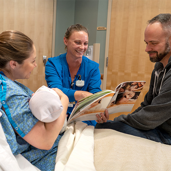 Discharge nurse showing new parents the Understanding Postpartum health and Baby Care book at the hospital