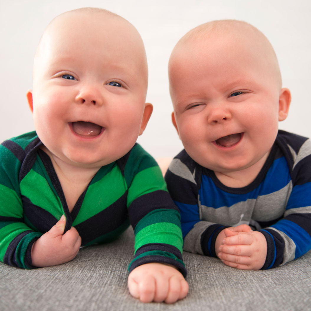 Smiling baby twins in striped shirts