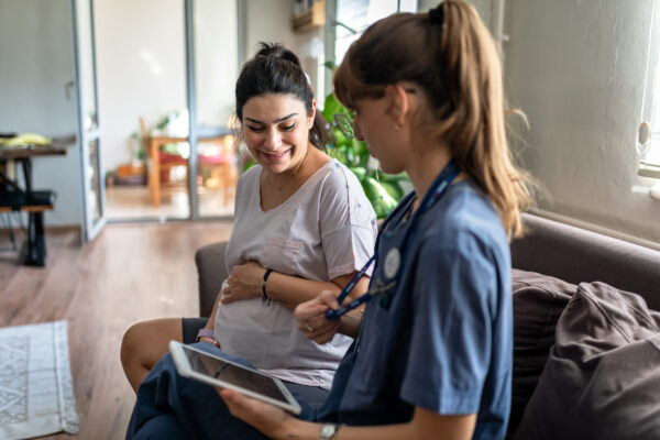 Home visitation nurse assisting a mother via an iPad