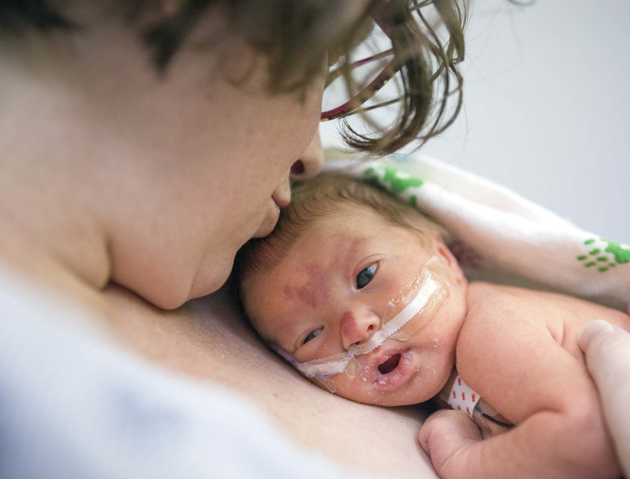 Mother holding her newborn baby in the Neonatal Intensive Care Unit (NICU)