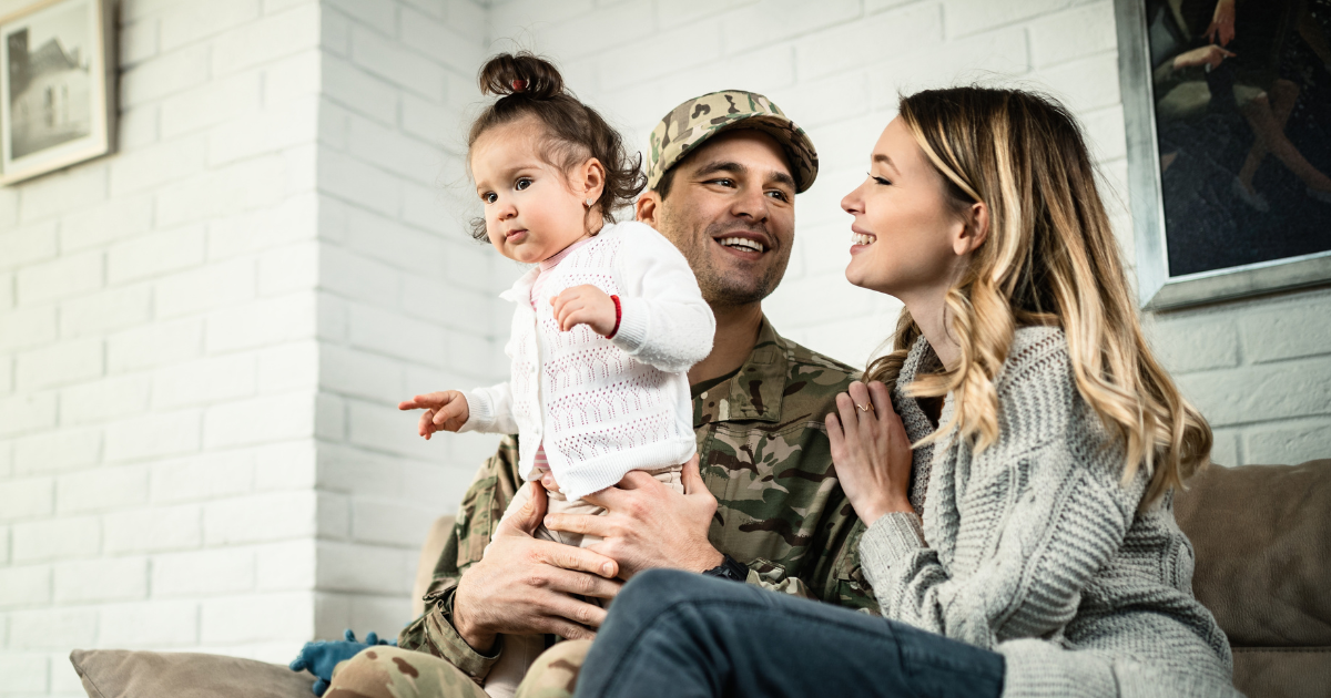 A dad in his military uniform and a mom holding their baby.
