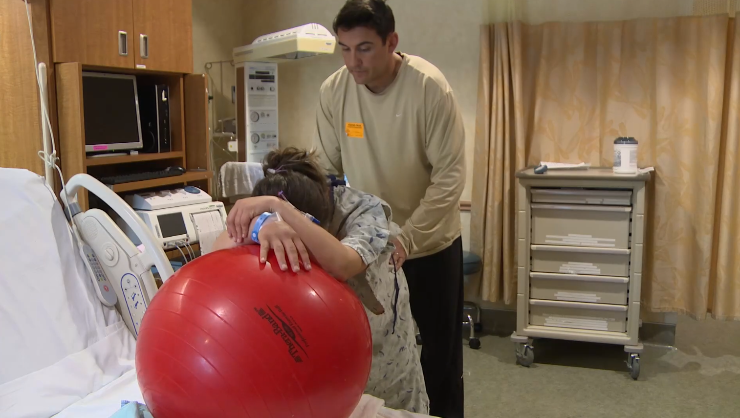 A husband helps his wife with labor pain by massaging her back.