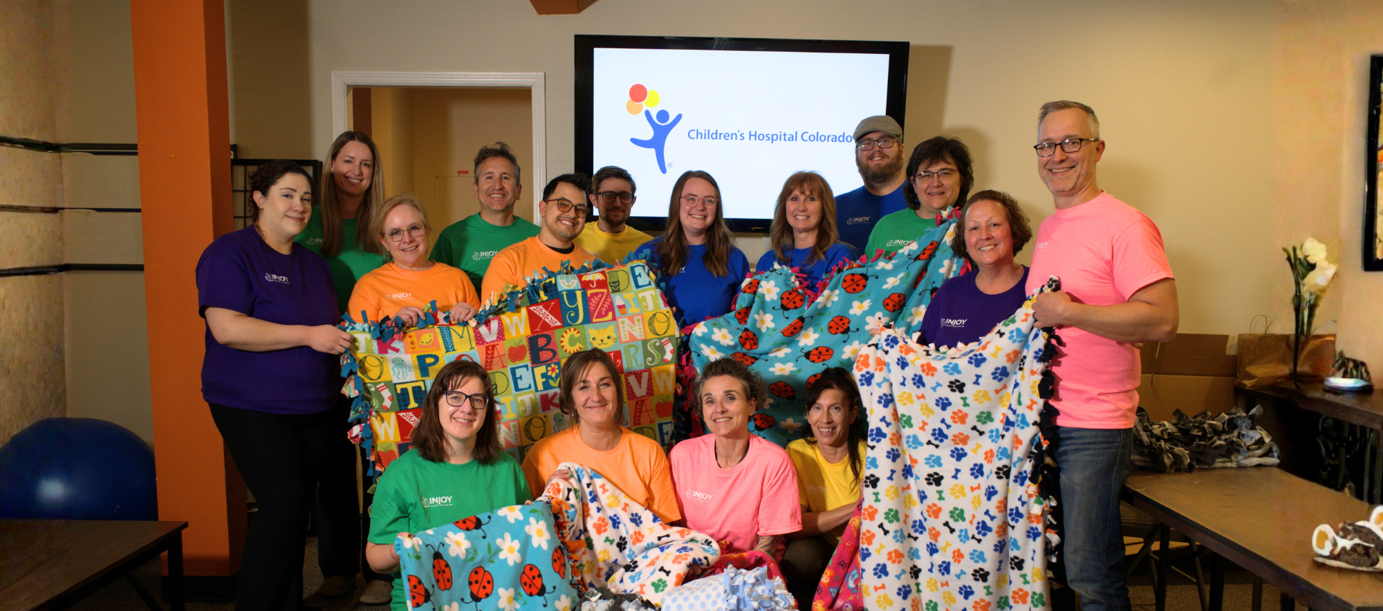 Group photo of the InJoy team demonstrating the fleece tie blankets they made for Children's Hospital Colorado.