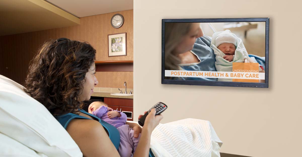 Woman in a hospital bed holding her newborn watching Understanding Postpartum Health & baby Care videos on a tv